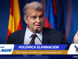 Politician speaking at a press conference behind a microphone, flags in the background, with a banner reading 'POLÉMICA ELIMINACIÓN' and 'Barcelona considera que fue perjudicado' at the bottom.