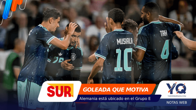 Group of soccer players in blue uniforms celebrate on the field, heads close in a moment of encouragement.