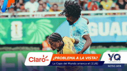 Two soccer players clash for the ball on a crowded stadium field, one in blue and one in yellow, with sponsor banners overlaid at the bottom and a blurred crowd in the background.