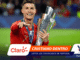 Cristiano Ronaldo celebrating with a tall silver trophy and medal on a football pitch.