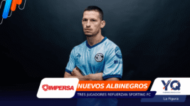 Portrait of a man in a light-blue jersey with arms crossed, standing against a dark gradient backdrop with colorful graphic overlays at the left and bottom edges, including sponsor logos.