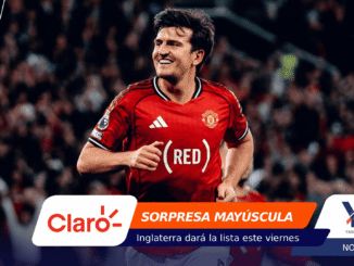 Manchester United player in a red kit running on the pitch during a crowded match, with colorful sponsor banners across the bottom.