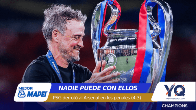 Man with gray hair smiles while holding a large silver trophy with blue and red ribbons during a celebration, stadium in the background.