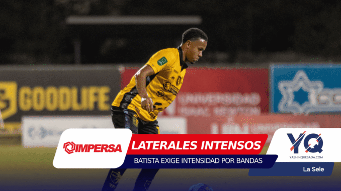 Soccer player in a yellow jersey running on the field with sponsor boards in the background during a night match, bib and logos visible on uniform.