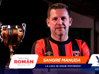 Portrait of a man in a red-and-black striped soccer jersey standing beside a silver trophy; sponsor banners cover the lower part of the image.