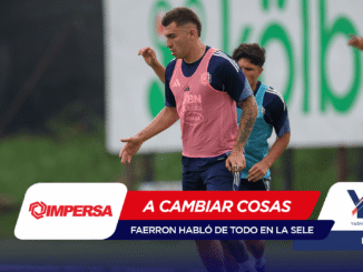 Soccer players sprinting on a training field; foreground player wears a pink bib while teammates practice, with sponsor banners across the bottom.