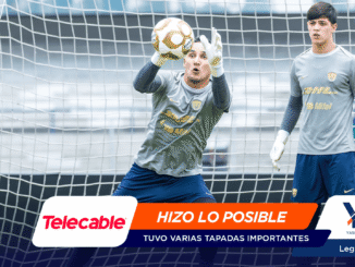 Two soccer goalkeepers in gray uniforms stand inside the goal net, one reaching for a ball, with sponsor banners across the bottom of the image