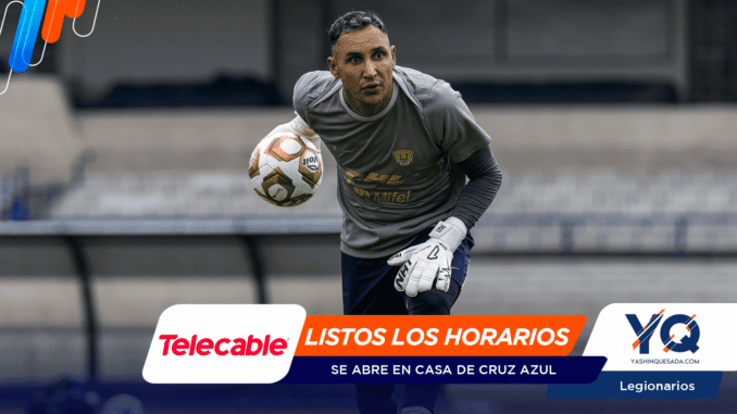 Soccer goalkeeper in gray shirt and white gloves reaches for a ball during training, blurred stadium seats in the background.