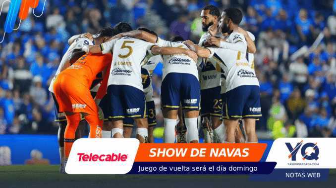 Soccer team huddling in a blue stadium, players in white and navy uniforms with orange goalie, banners at bottom display sponsors like Telecable and YQ Vivans.