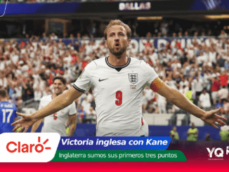 England striker Harry Kane celebrates a goal with arms outstretched as a full stadium cheers behind him, wearing England white kit with number 9