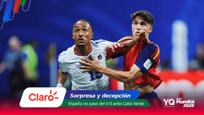Two soccer players clash for the ball during a match: one in white and blue, the other in red and blue, with colorful sponsor banners at the bottom.