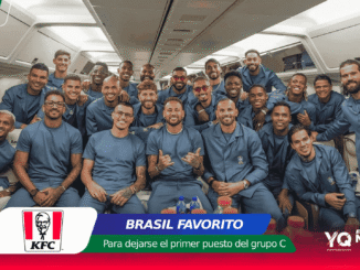 Group of athletes in matching blue outfits posing together inside an airplane cabin, smiling at the camera.