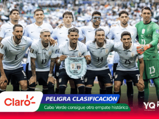 Uruguay national football team players pose for a group photo on the pitch, goalkeeper in green on the right, crowd in the stands behind them.