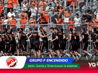 Men's basketball or soccer team in black and orange uniforms run past a cheering crowd of orange-clad fans behind a fence.
