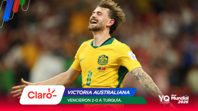 Australian soccer player in yellow jersey celebrates with arms outstretched, smiling