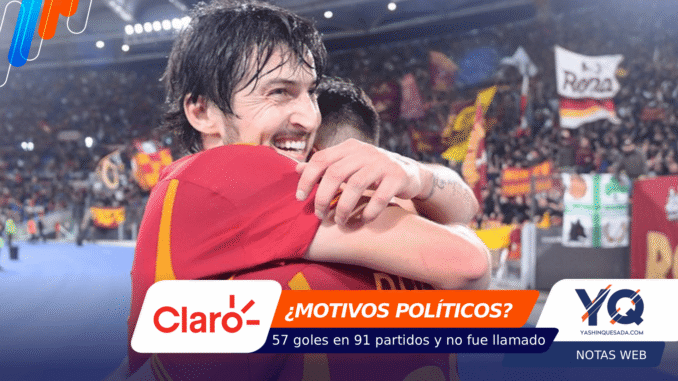 Two soccer players hug on a crowded stadium field after a match, celebrating a win: the scene is full of fans and banners in the background.
