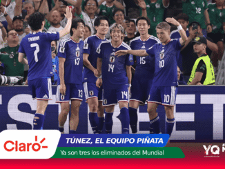 Japanese futsal team in blue jerseys celebrate on the court, high-fiving and smiling as fans cheer in the background