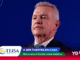 Man in a dark suit and teal tie on a stage with a solid dark blue background, bottom banner showing TEISA logo and Mundial 2026 branding.