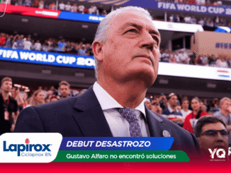 Close-up of a man in a suit at a stadium, with FIFA World Cup 2026 banners and sponsor graphics in the foreground.
