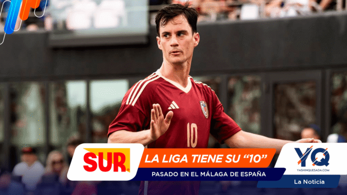 Soccer player in a maroon jersey with number 10 raises a hand on the field, with colorful sponsor banners across the bottom.