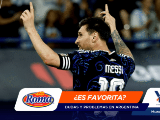 Male soccer player with short dark hair and a tattooed right arm raises his arms in celebration on a promotional banner, jersey reads 'MESSI 10', with Roma and YQ logos and the text '¿ES FAVORITA?' on an orange banner for Mundial 2026.