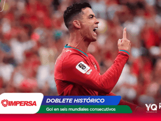 Soccer player in a red jersey celebrates with a raised finger as fans blur in the red stadium backdrop.