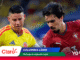 Two soccer players, one in a Colombia yellow jersey and the other in Portugal red, contest the ball in action on the field with sponsor banners overlaying the image.