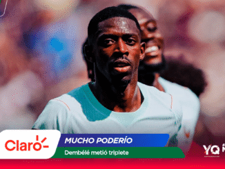 Soccer player in a light turquoise jersey running on a blurred stadium field with colorful sponsor graphics at the bottom edge.