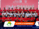 Group of men in red polo shirts and light-blue shirts posing on bleachers at a Panama Copa Airlines event, with a pink backdrop that says 'Vamos Panamá'.