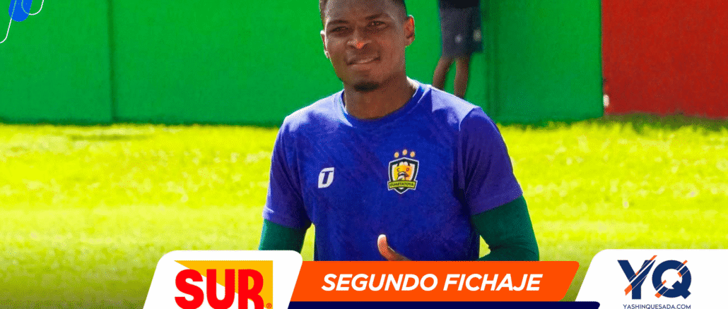 Portrait of a smiling male soccer player in a blue jersey on a sunny grassy field, with vibrant sponsor banners overlaid (SUR, SEGUNDO FICHAJE).