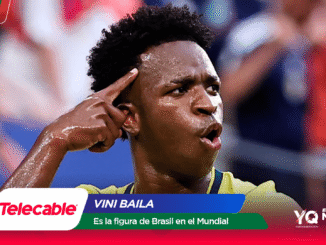 Brazilian footballer celebrates a goal, pointing to his temple with a sweaty yellow jersey and a blurred stadium crowd behind; sponsor graphics at the bottom.