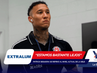 Tattooed man with wireless earbud wearing a polo, speaking at a press interview with banner graphics overlaid at the bottom.