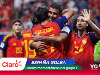 Spain national team players celebrate a goal in red-yellow uniforms, embracing on the pitch amid a cheering crowd, with sponsor graphics overlayed (Claro, España Golea).