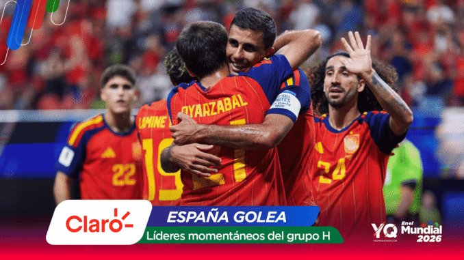 Spain national team players celebrate a goal in red-yellow uniforms, embracing on the pitch amid a cheering crowd, with sponsor graphics overlayed (Claro, España Golea).