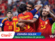 Spain national team players celebrate a goal in red-yellow uniforms, embracing on the pitch amid a cheering crowd, with sponsor graphics overlayed (Claro, España Golea).