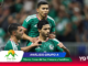 Three Mexican national team players celebrate on the soccer field in green jerseys, crowd blurred in the background.