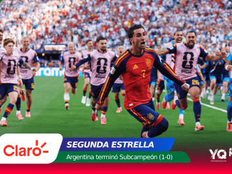 Spain national team player in red #7 sprinting on a crowded field with teammates in pink bibs behind and a stadium full of fans; bottom sponsor banner visible.