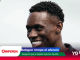 Close-up of a smiling Black man with a light background and colorful banner graphics at the bottom edge.
