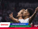 Two soccer players in white celebrate with arms raised on a dark stadium background; digital banners at the bottom show 'Resultado histórico' and sponsor logos.