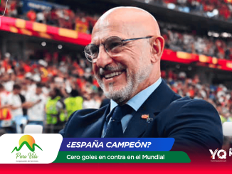 Smiling bald man in a suit at a stadium with colorful banners and a cheering crowd in the background (celebration scene).