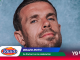 Close-up of a man tilting his head against a blue backdrop, overlaid with Roma logo and text about a broken arm celebration for Mundial 2026.