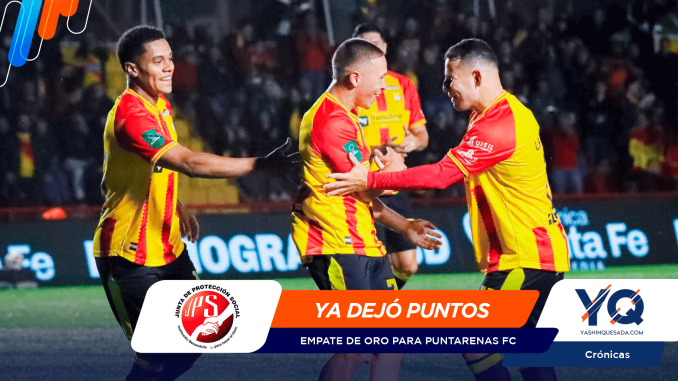 Three football players in yellow-red kits celebrate and embrace on a crowded stadium field, smiling after a play, with sponsor banners overlaid at the bottom.