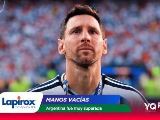 Soccer player with medal around neck in a stadium, crowd blurred in the background with sponsor banners in the foreground.