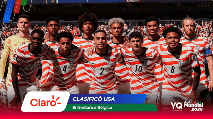 United States men's soccer team posing together on the field in red and white striped jerseys with a crowd in the background.