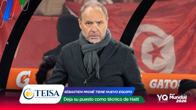 Man in a dark coat and gray scarf seated on a television sports set with red banners and sponsor logos in the background