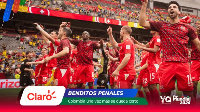 Soccer players in red uniforms celebrate on the field, raising their arms as fans cheer in the stadium stands behind them.