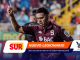 Soccer player in a maroon jersey raises one finger in celebration on a rainy stadium, with colorful sponsor banners at the bottom reading NUEVO LEGIONARIO and related logos in view.