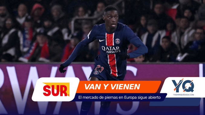 Soccer player in PSG kit runs on the field during a match, 광고 banners in the foreground and crowd in the stands behind him.