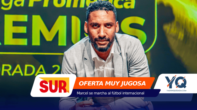 Portrait of a man in a light gray blazer speaking at a sports event, with bold SUR and Oferta Muy Jugosa banners in the foreground