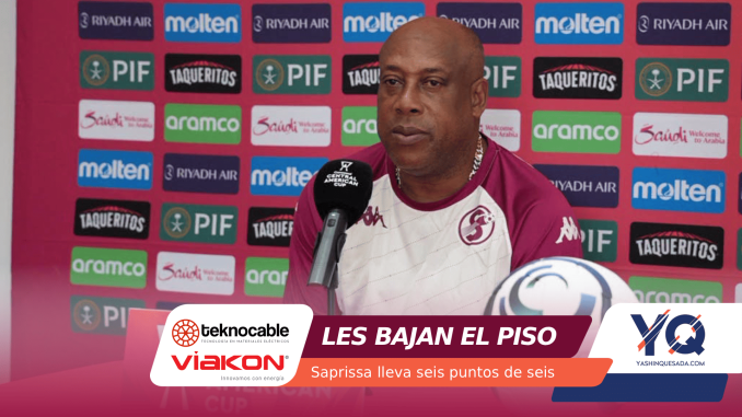 Man in maroon and white sports jersey speaking at a press conference in front of a pink sponsor wall featuring Riyadh Air, Molten, PIF, Aramco logos.